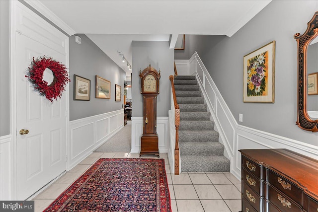 entrance foyer featuring light tile patterned floors, a wainscoted wall, stairway, and a decorative wall