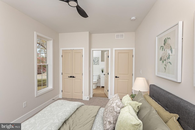 carpeted bedroom with ensuite bathroom, baseboards, visible vents, a closet, and ceiling fan