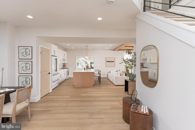 corridor featuring baseboards, recessed lighting, and light wood-style floors