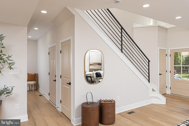 foyer featuring baseboards, visible vents, recessed lighting, light wood-style floors, and stairs