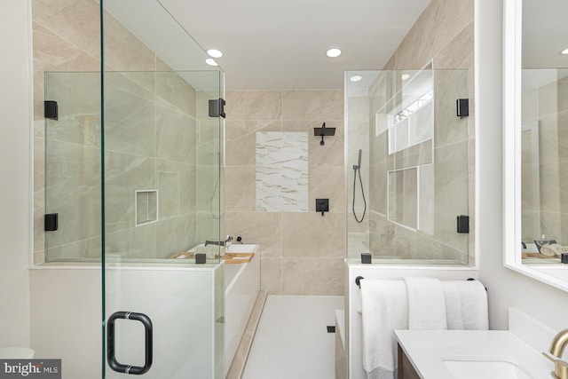 full bath featuring recessed lighting, tile walls, vanity, and a stall shower