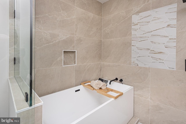 full bathroom with a freestanding bath, an enclosed shower, and tile walls