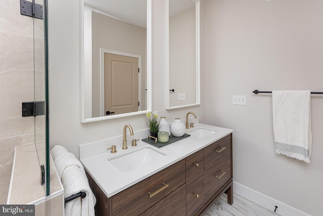 full bath featuring marble finish floor, baseboards, a sink, and double vanity