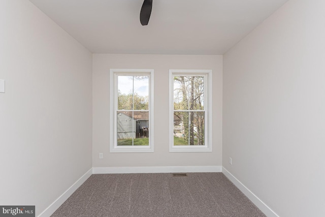spare room featuring a ceiling fan, baseboards, and dark carpet