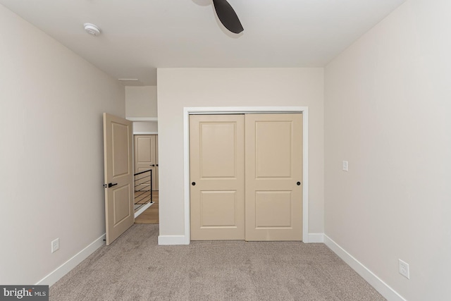 unfurnished bedroom with ceiling fan, baseboards, a closet, and light colored carpet