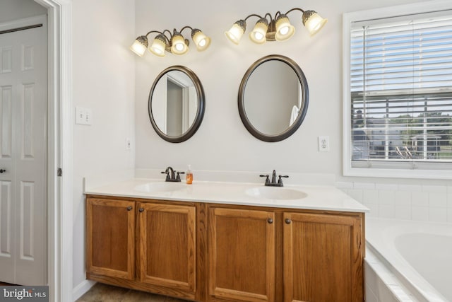 full bathroom with a sink, tiled tub, and double vanity