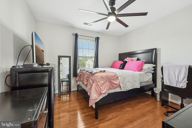 bedroom with a ceiling fan, baseboards, visible vents, and wood finished floors