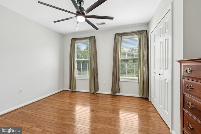 unfurnished bedroom with baseboards, multiple windows, light wood-type flooring, and visible vents