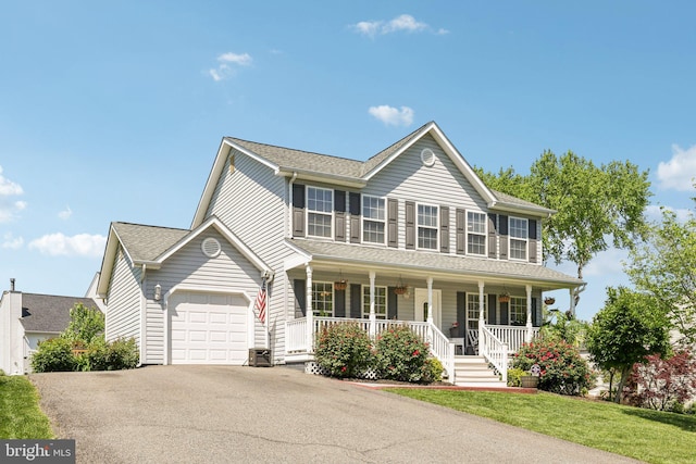 colonial-style house featuring a porch, driveway, roof with shingles, a front yard, and a garage