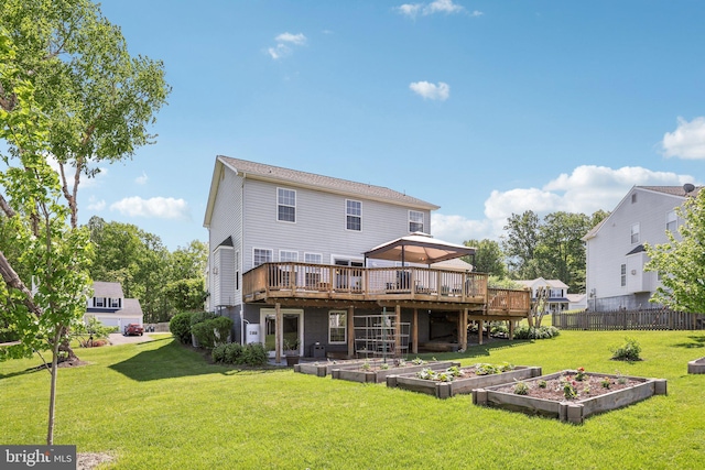 back of property featuring a yard, a vegetable garden, a deck, and fence