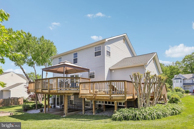 rear view of property featuring a deck, a patio area, fence, a yard, and a shingled roof