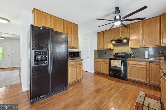 kitchen featuring ceiling fan, under cabinet range hood, tasteful backsplash, light wood finished floors, and black appliances