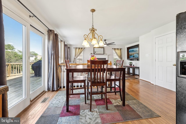 dining space with an inviting chandelier, a wealth of natural light, wood-type flooring, and visible vents