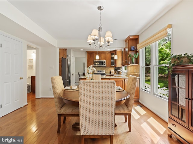 dining space with an inviting chandelier, light wood finished floors, and baseboards