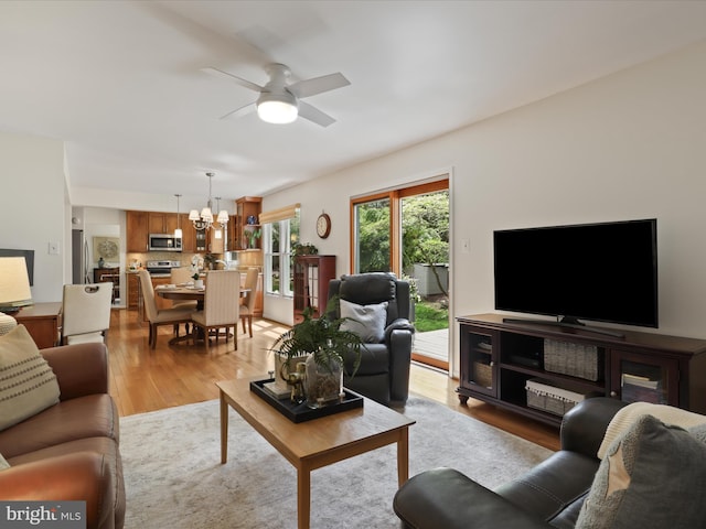 living room with light wood finished floors and ceiling fan with notable chandelier