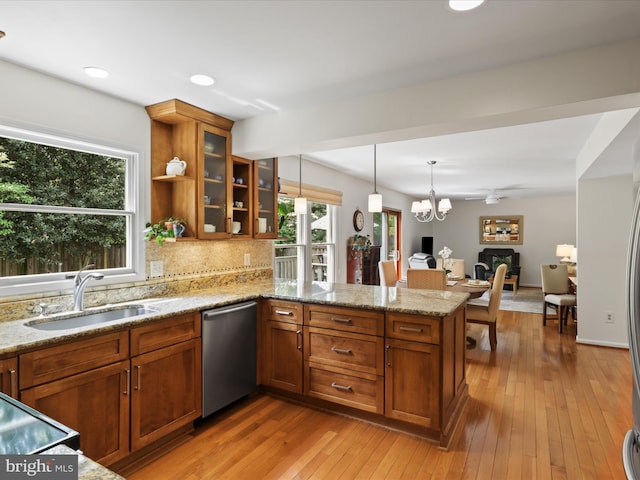 kitchen with stainless steel dishwasher, a peninsula, a sink, and brown cabinets