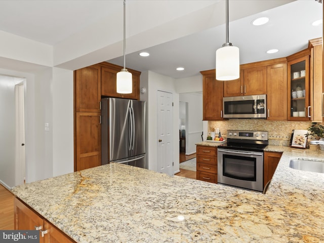 kitchen with light stone counters, brown cabinets, and stainless steel appliances