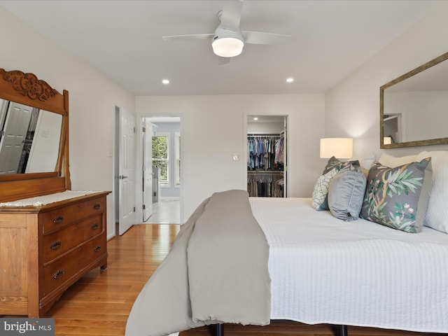 bedroom with light wood-type flooring, a closet, recessed lighting, and a walk in closet