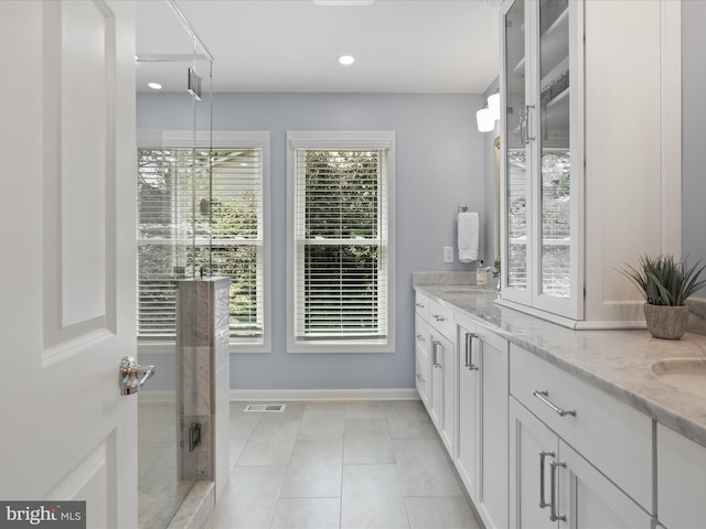 full bathroom featuring double vanity, a sink, baseboards, visible vents, and a stall shower