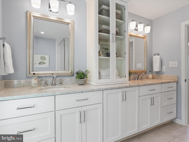 full bathroom with double vanity, tile patterned flooring, and a sink
