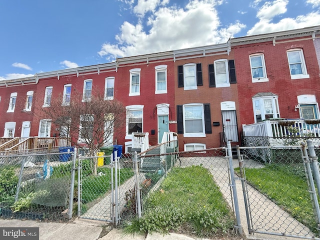 view of property featuring a fenced front yard, a gate, and brick siding