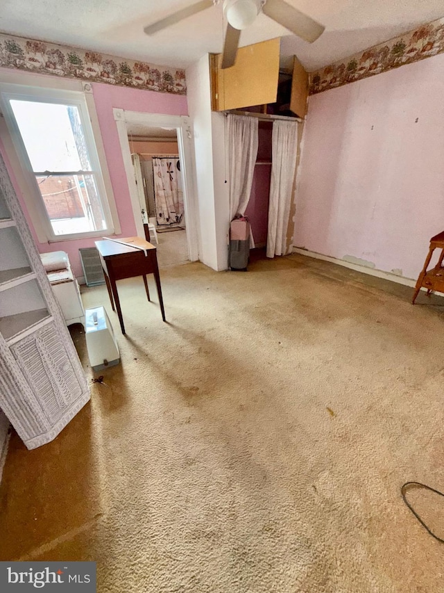 interior space featuring a ceiling fan and carpet floors