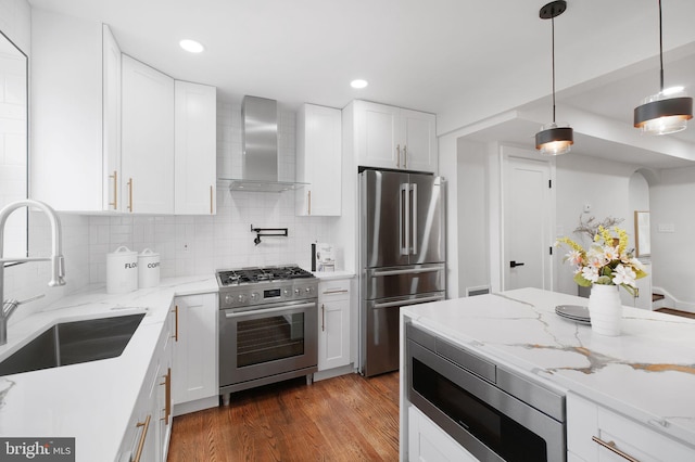133 Ingraham St NW, Washington, DC 20011 - kitchen with white cabinetry, backsplash, wall chimney exhaust hood, appliances with stainless steel finishes, and a sink