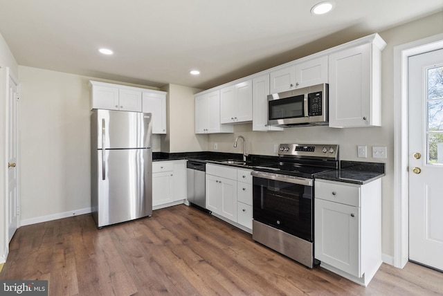 kitchen with white cabinetry, dark wood-style floors, stainless steel appliances, and a sink
