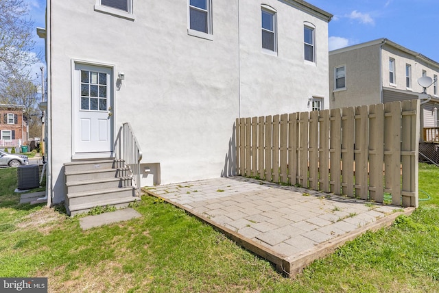 exterior space with stucco siding, entry steps, central AC unit, and fence