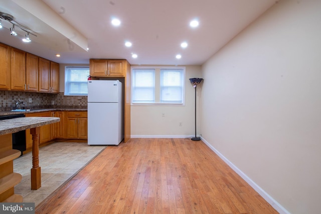 7834 Fayette St, Philadelphia, PA 19150 - kitchen with light wood-type flooring, brown cabinetry, freestanding refrigerator, and backsplash