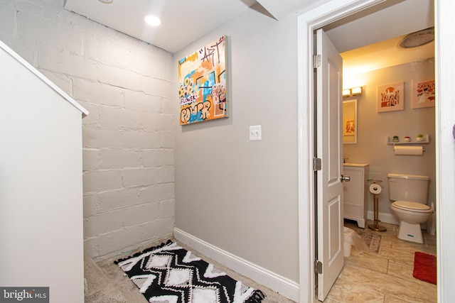 hallway featuring baseboards and concrete block wall