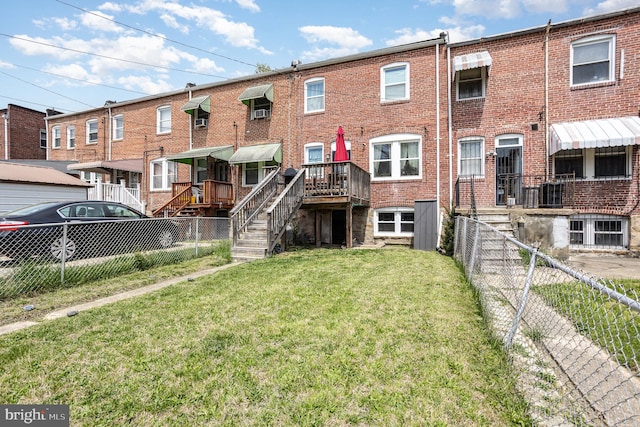 rear view of house featuring a lawn, brick siding, and fence private yard
