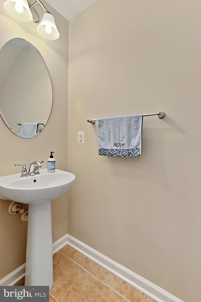 bathroom featuring baseboards, tile patterned floors, and a sink