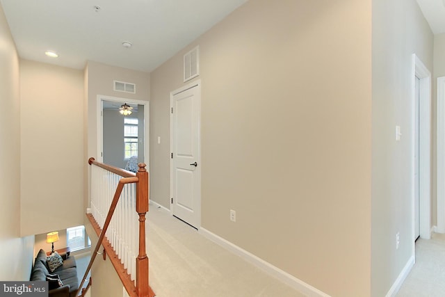 hall featuring visible vents, light carpet, and an upstairs landing