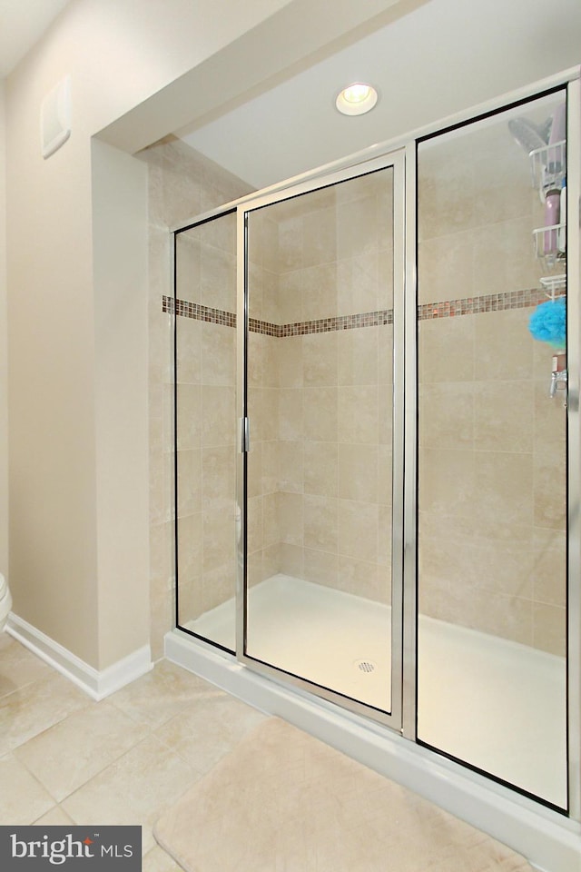 full bathroom with toilet, tile patterned flooring, and a stall shower