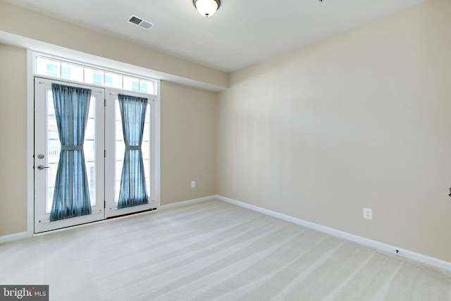 empty room with baseboards, visible vents, light colored carpet, and french doors