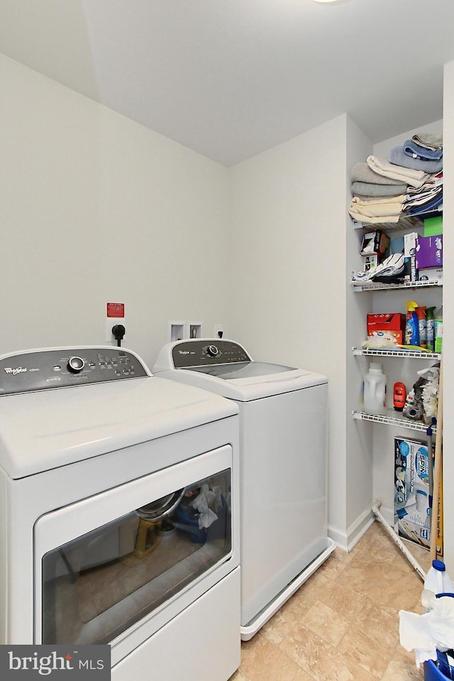 laundry area with washing machine and clothes dryer, baseboards, and laundry area