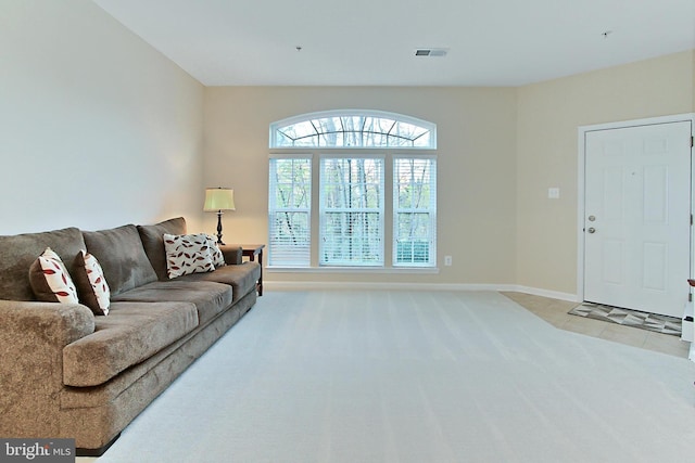 living room featuring baseboards, visible vents, light colored carpet, and light tile patterned floors