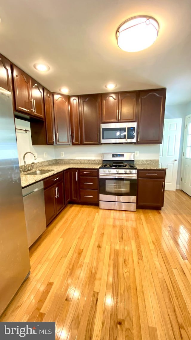 8107 Candle Ln, Baltimore, MD 21237 - kitchen featuring stainless steel appliances, light wood-style flooring, a sink, dark brown cabinetry, and light stone countertops