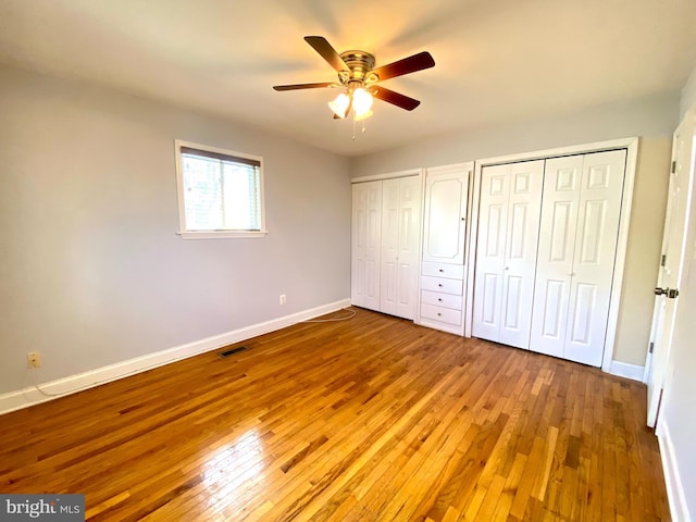 8107 Candle Ln, Baltimore, MD 21237 - unfurnished bedroom featuring baseboards, visible vents, two closets, ceiling fan, and hardwood / wood-style floors