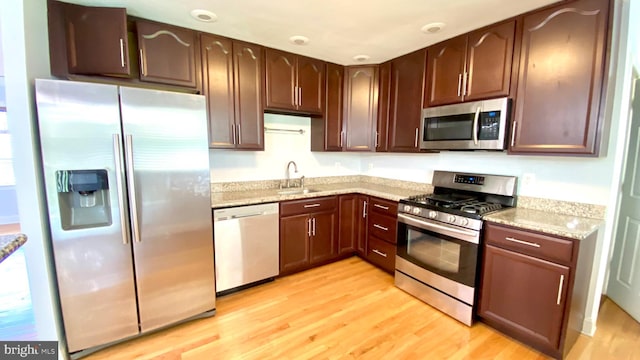 8107 Candle Ln, Baltimore, MD 21237 - kitchen with light stone counters, a sink, dark brown cabinetry, light wood-style flooring, and appliances with stainless steel finishes