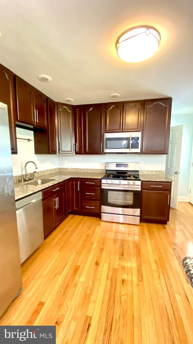 8107 Candle Ln, Baltimore, MD 21237 - kitchen featuring light stone counters, light wood finished floors, stainless steel appliances, and a sink
