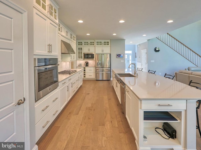 22144 Welches Way, Lewes, DE 19958 - kitchen with appliances with stainless steel finishes, under cabinet range hood, a sink, a large island with sink, and light wood-style flooring