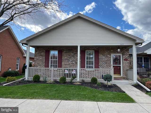bungalow-style house with brick siding, a front yard, and covered porch