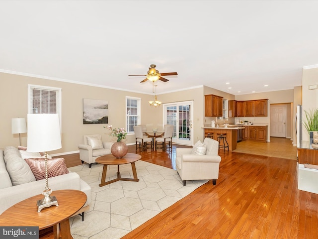 living area with crown molding, a ceiling fan, and light wood-style floors