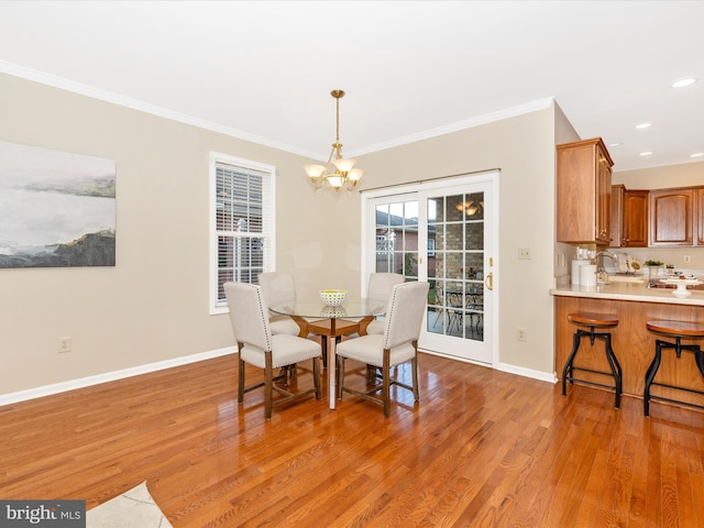 dining room featuring crown molding, baseboards, a notable chandelier, and light wood-style floors