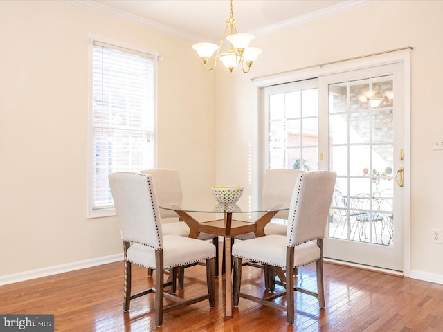 dining room featuring an inviting chandelier, ornamental molding, hardwood / wood-style floors, and a healthy amount of sunlight