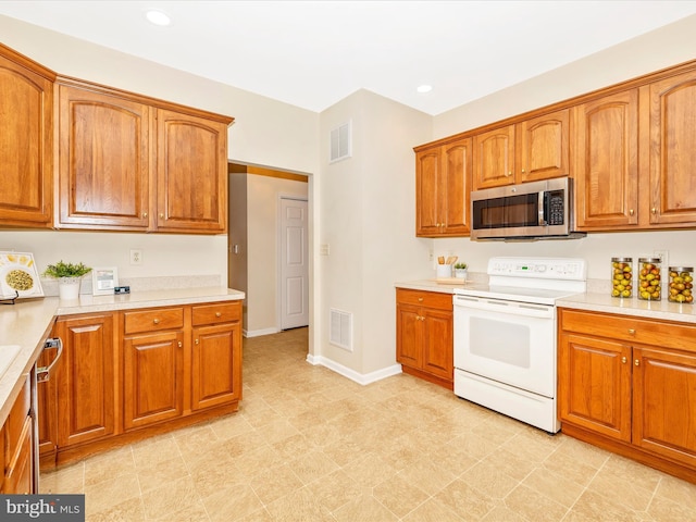 kitchen featuring brown cabinetry, appliances with stainless steel finishes, visible vents, and light countertops