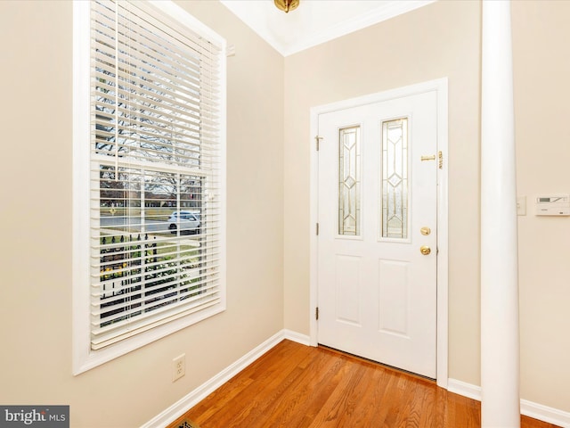 entrance foyer with wood finished floors, baseboards, a wealth of natural light, and crown molding