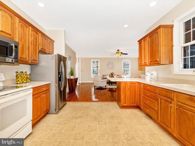 kitchen featuring brown cabinets, stainless steel appliances, light countertops, a sink, and ceiling fan
